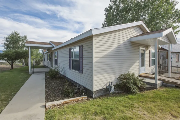 Cream-colored siding exterior featuring multiple covered entryways, purple window shutters, and a concrete pathway
