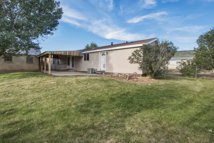 Rear exterior featuring a covered patio, concrete slab, and light-colored siding