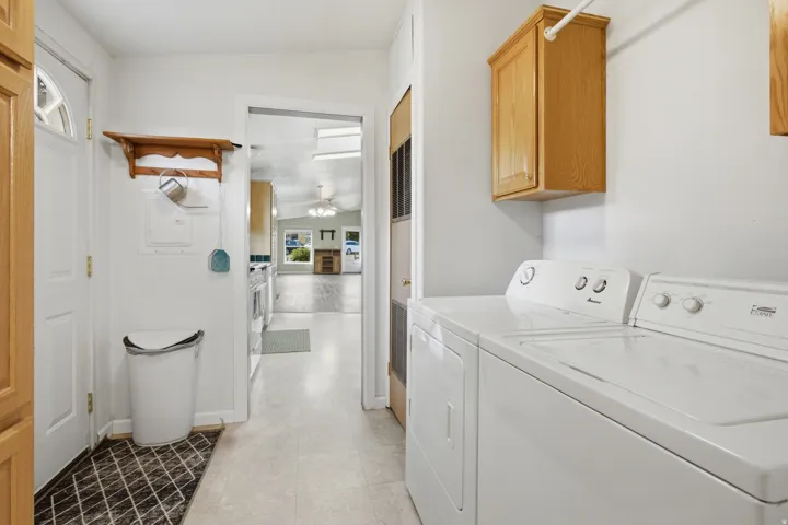 Dedicated laundry area featuring a light wood-finish upper cabinet, a wall-mounted drying rod, and durable flooring