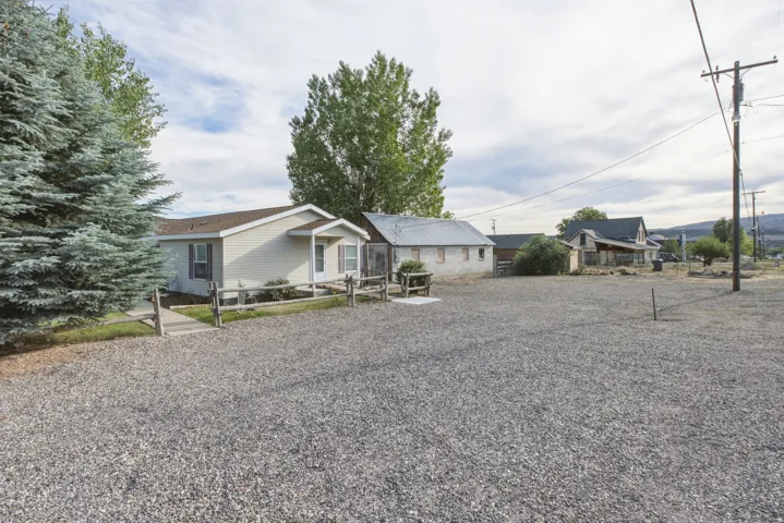 Gravel lot with a single-story home featuring light-colored siding, a covered entry, and a pitched roof