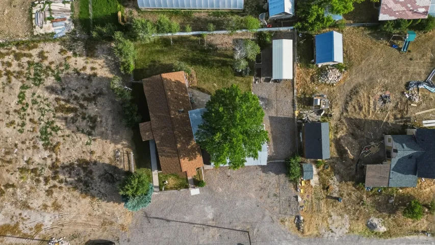 Property featuring a brown shingle roof, established green trees and multiple outbuildings