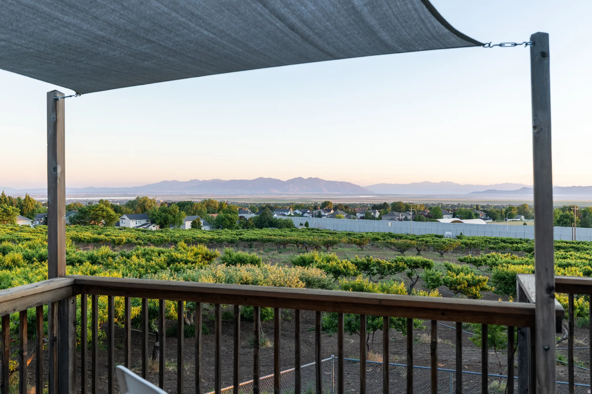 Upper-level outdoor deck featuring a shade canopy, wood railing, and posts