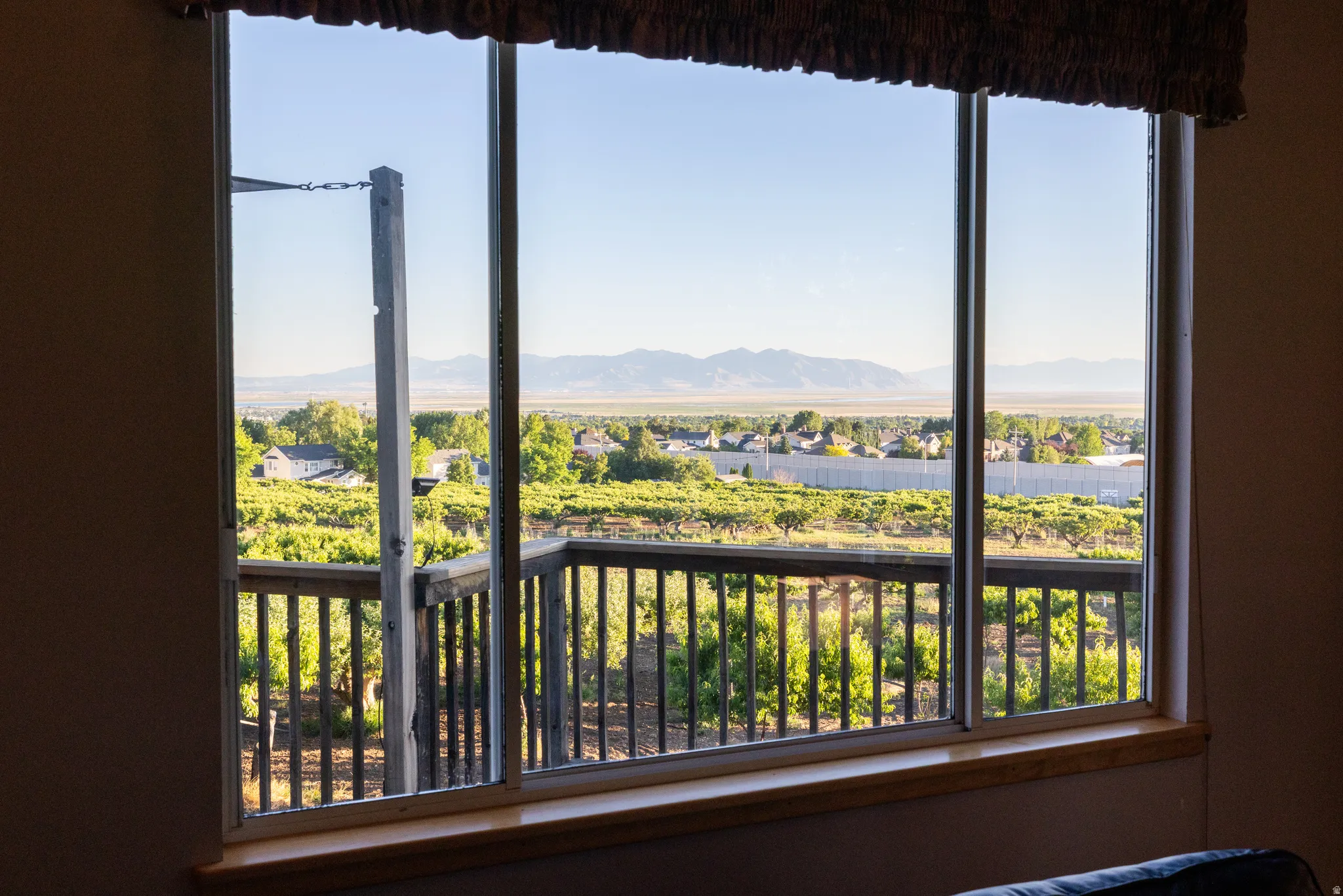Expansive window featuring a distant mountain range, community landscape, and vineyard scenery