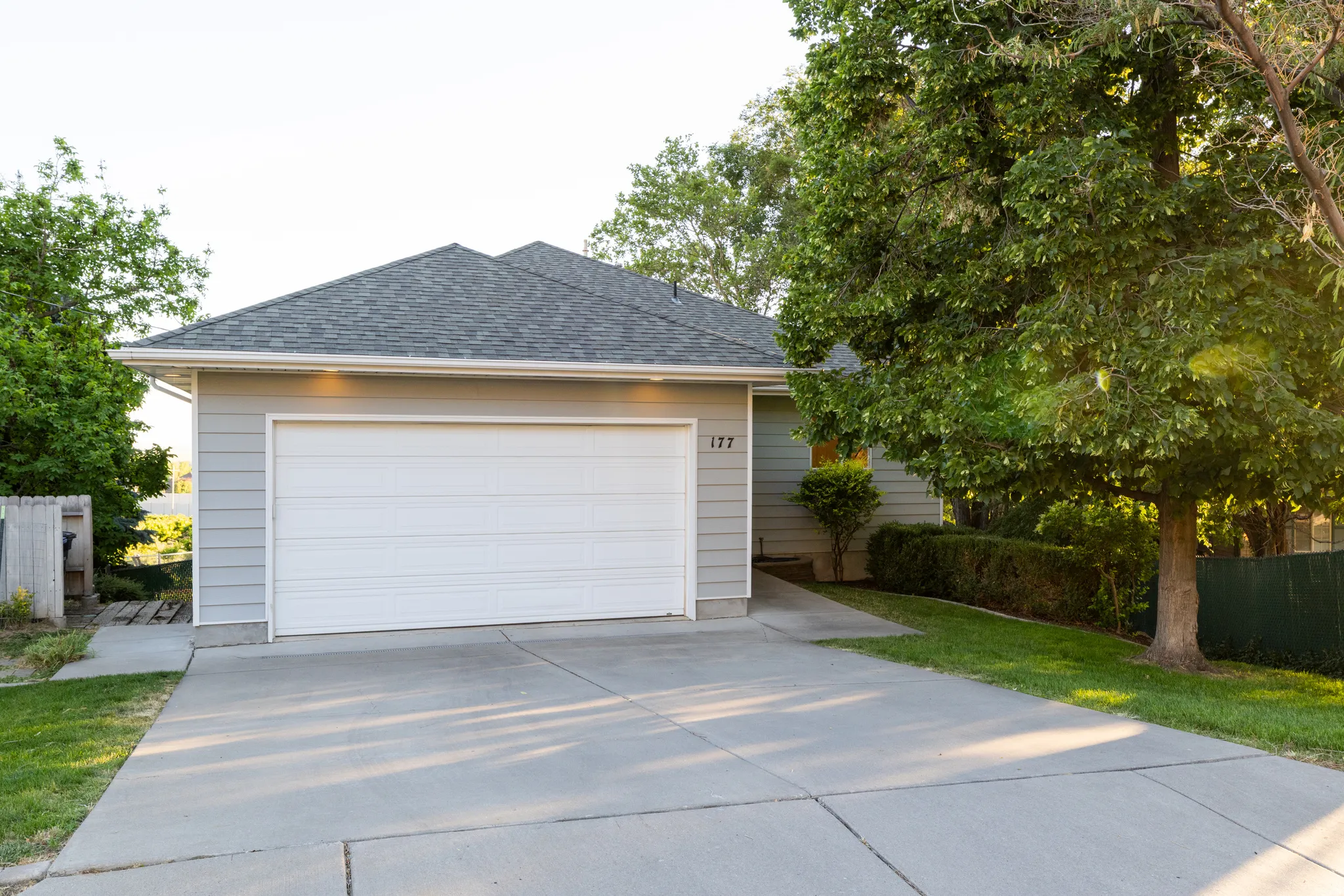 Single-story residence featuring light gray siding and a dark shingle roof