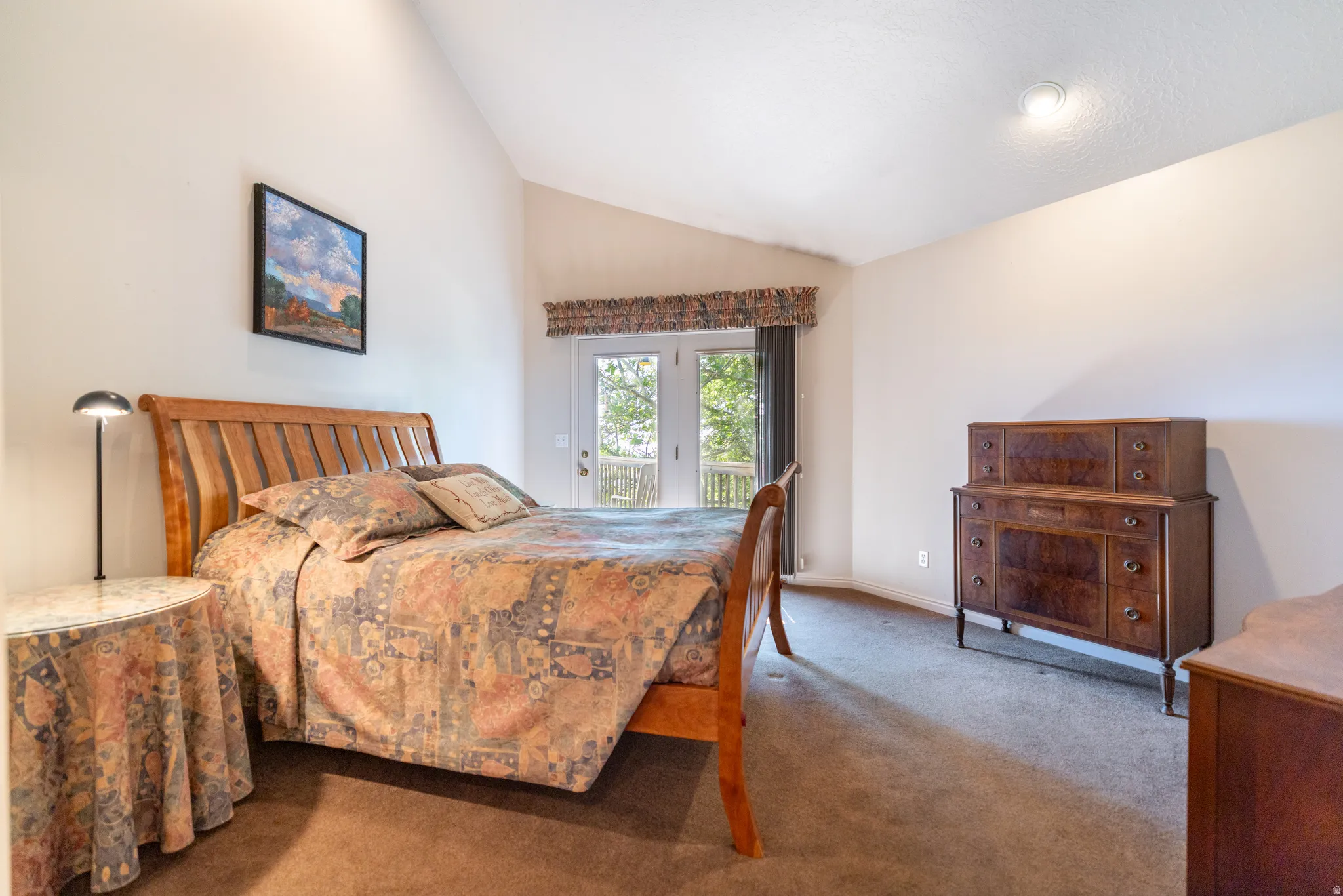 Spacious room featuring vaulted ceilings, a glass-paneled door leading to an exterior deck, soft brown carpeting, and recessed lighting