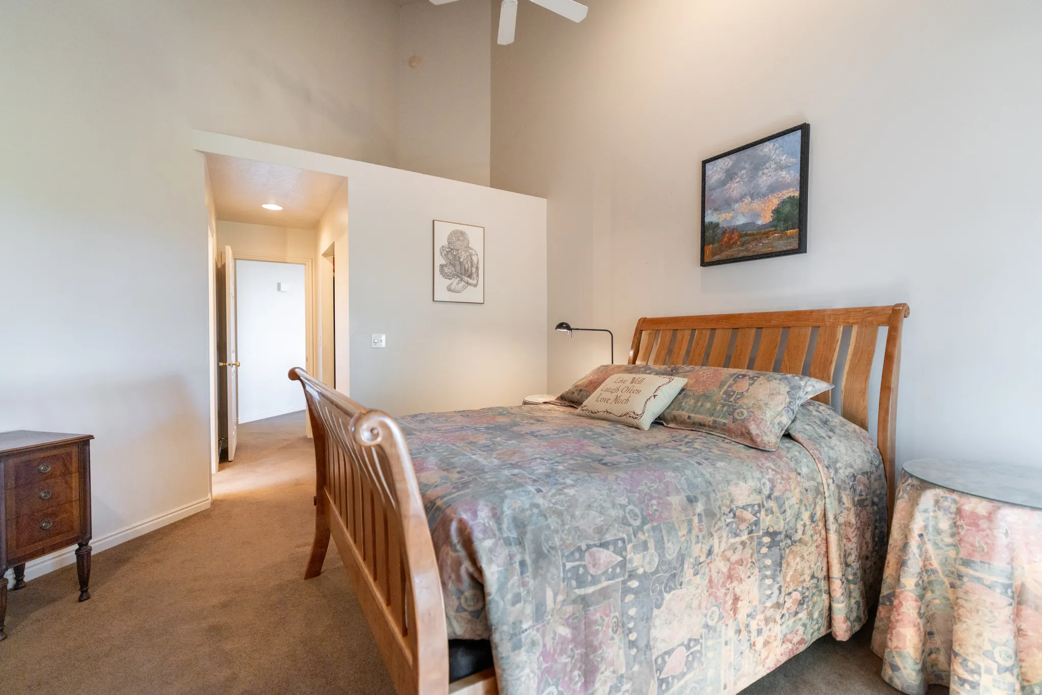 Carpeted bedroom featuring vaulted ceilings, a ceiling fan, and a hallway entrance with a recessed light fixture