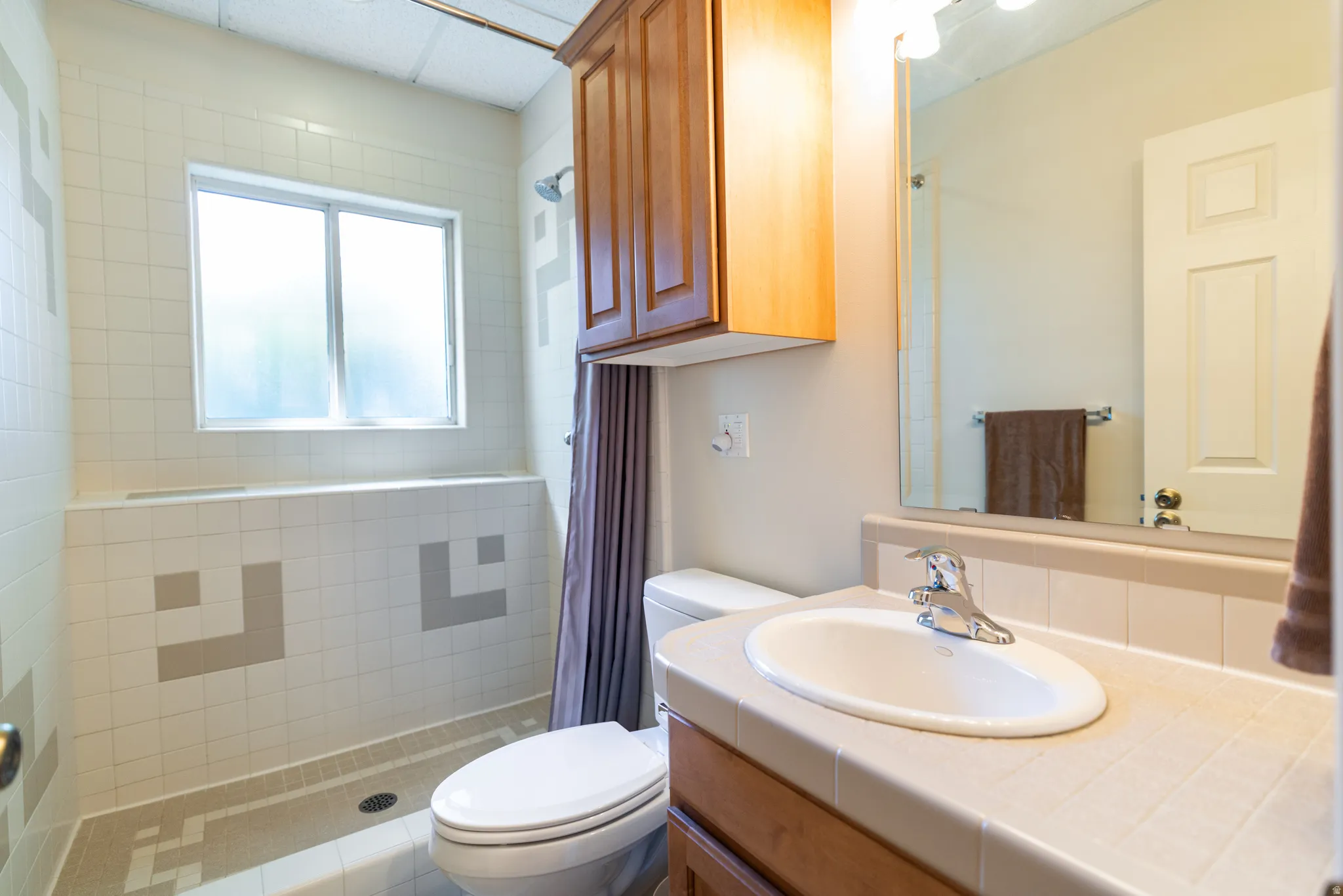 Bathroom featuring a tiled vanity with an integrated sink, chrome faucet, and a wall-mounted mirror