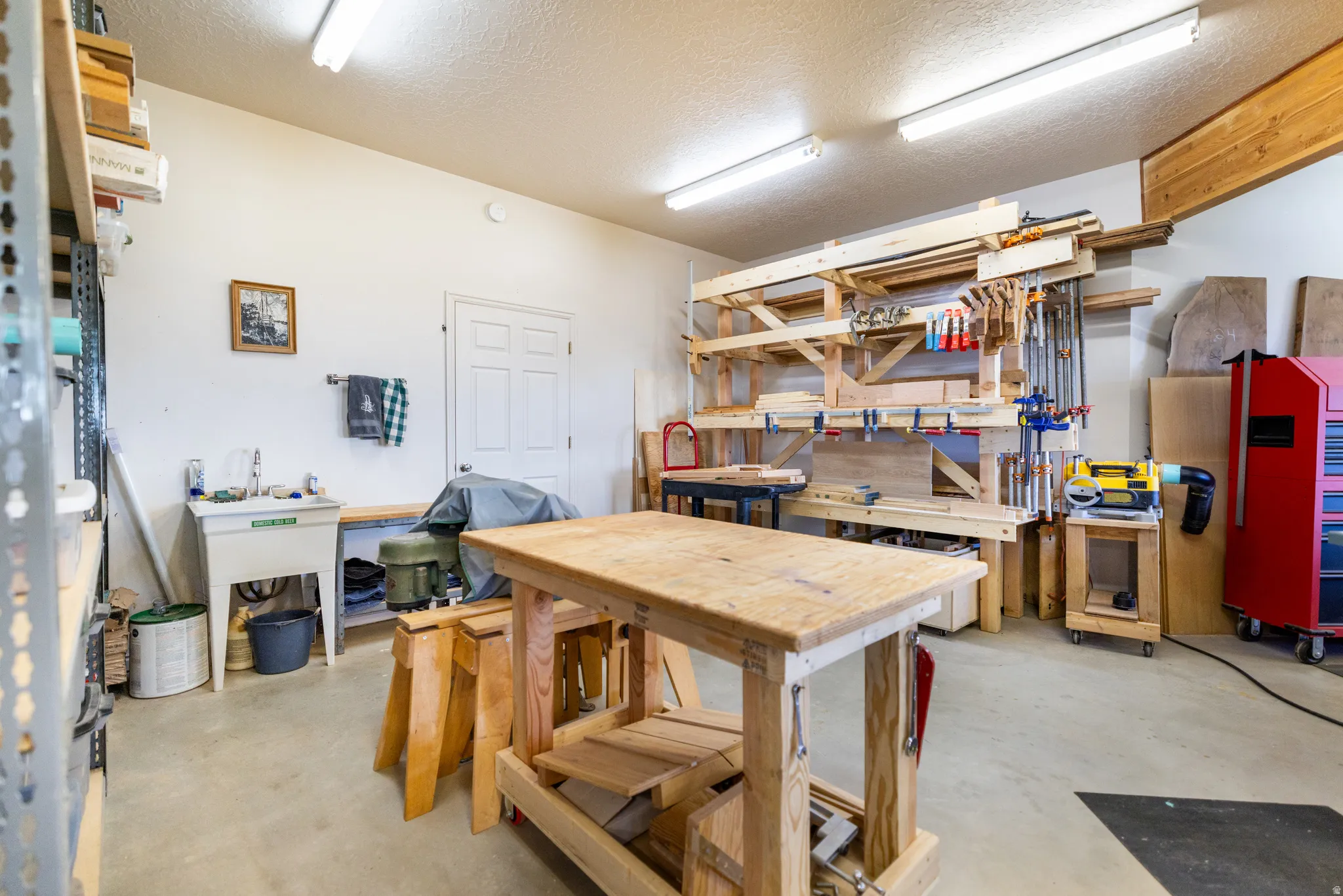Spacious garage featuring a concrete floor, built-in utility sink, and overhead fluorescent lighting