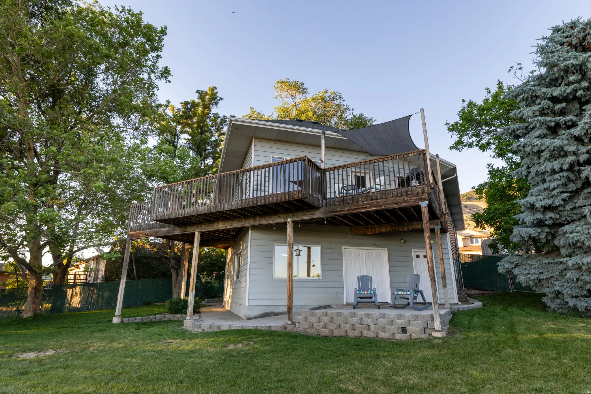 Rear exterior showcasing a multi-level deck, light gray siding, and a spacious lawn