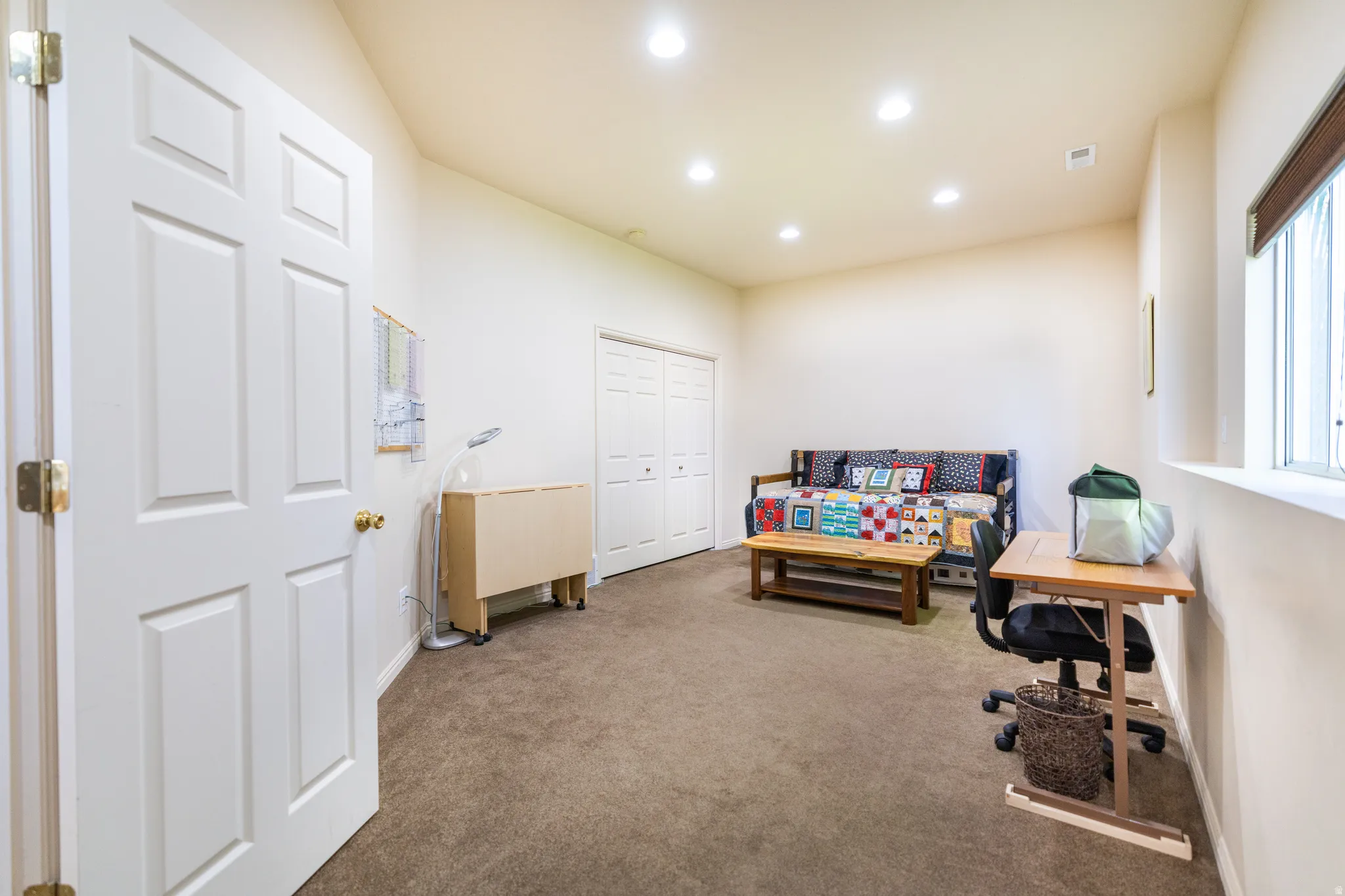Spacious room featuring neutral carpeting, recessed lighting, and a white six-panel door