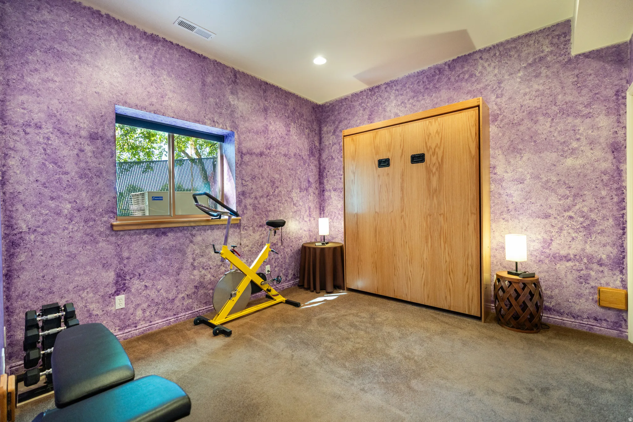 Room featuring textured purple walls, recessed lighting, and a built-in wood-paneled Murphy bed