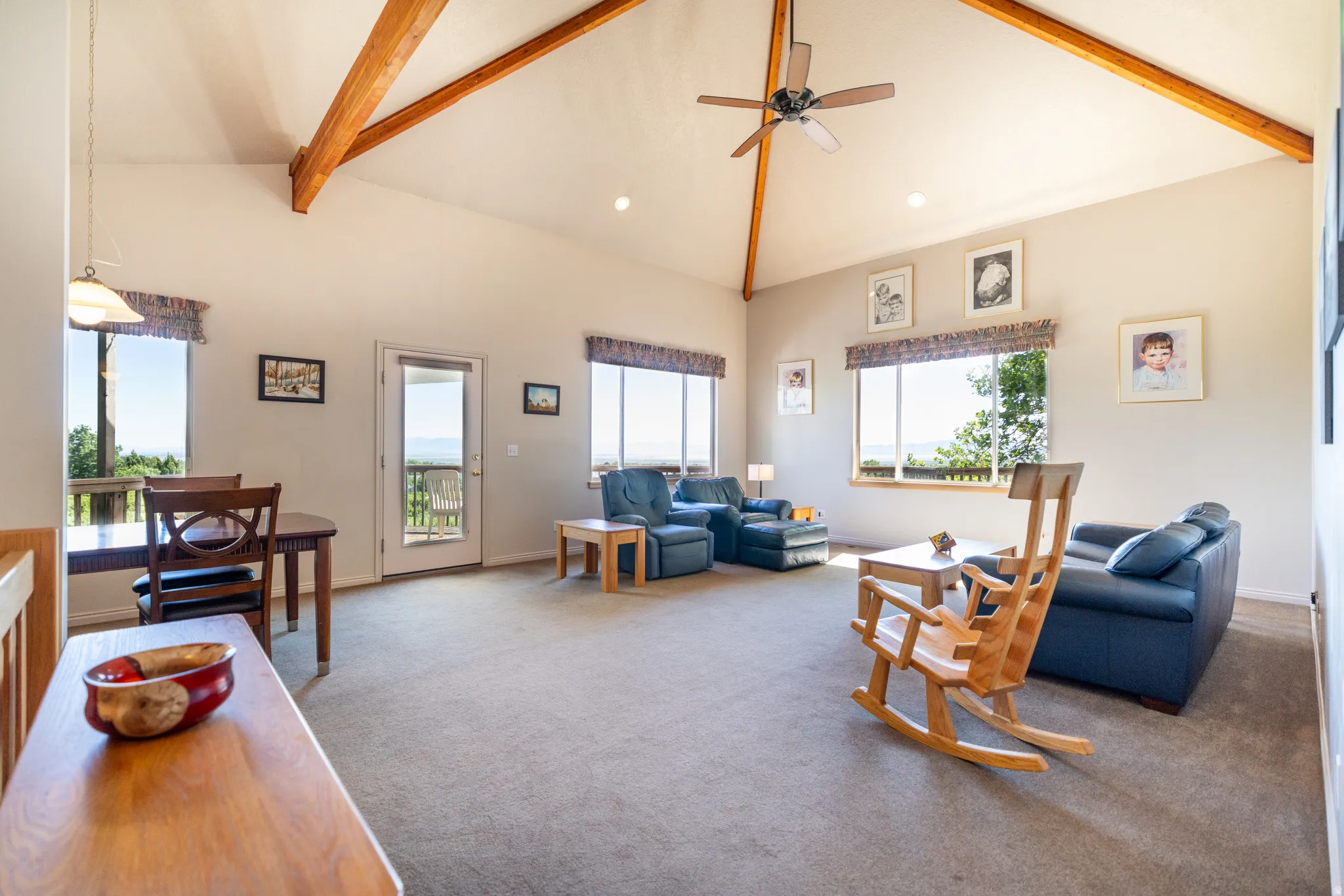 Spacious living area featuring a vaulted ceiling with exposed wood beams, recessed lighting, and a ceiling fan