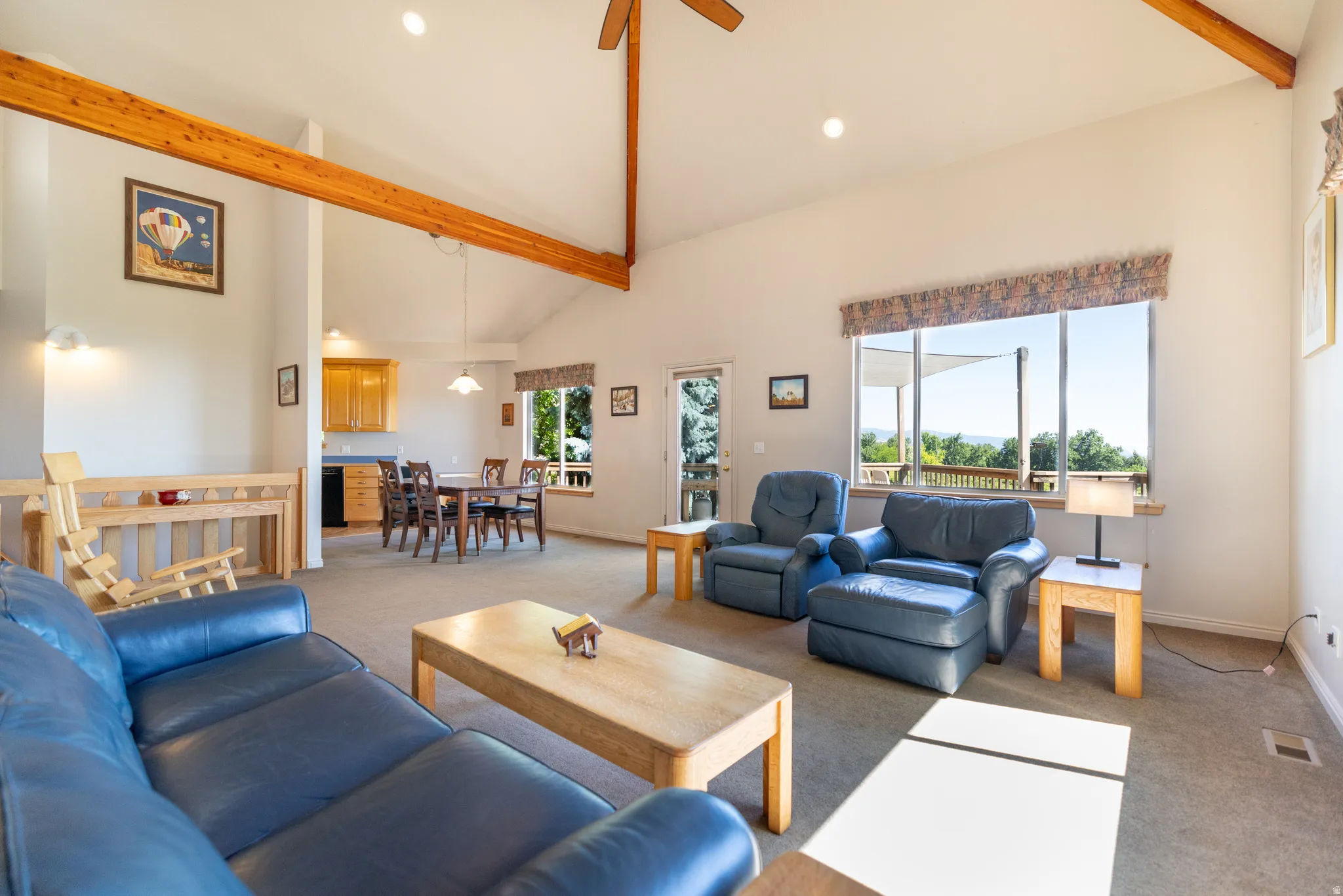 Vaulted ceilings with exposed wood beams, expansive windows, recessed lighting, and a neutral carpeted floor