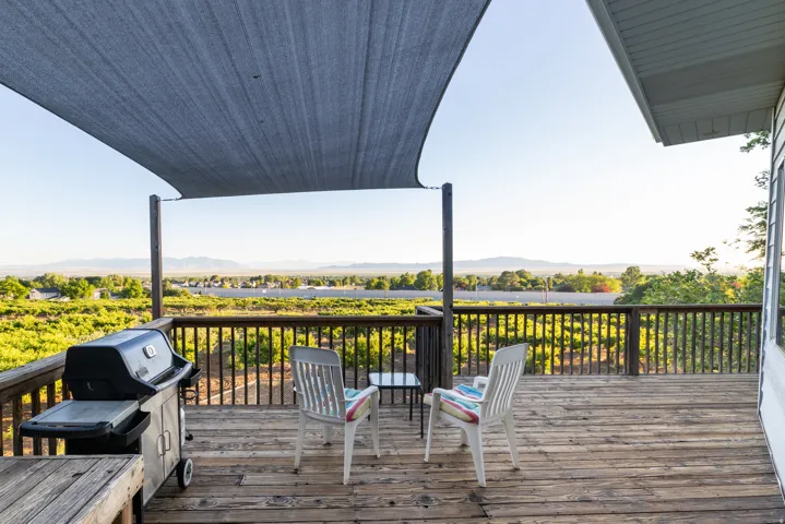 Expansive wood deck with a partial shade sail, wood railing, and surrounding landscape with distant mountains