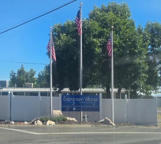 Evergreen Village signage with three flagpoles displaying American flags