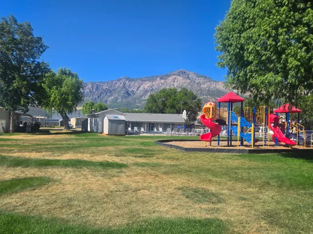 Expansive outdoor area featuring a colorful playground with slides and climbing structures on a wood chip base