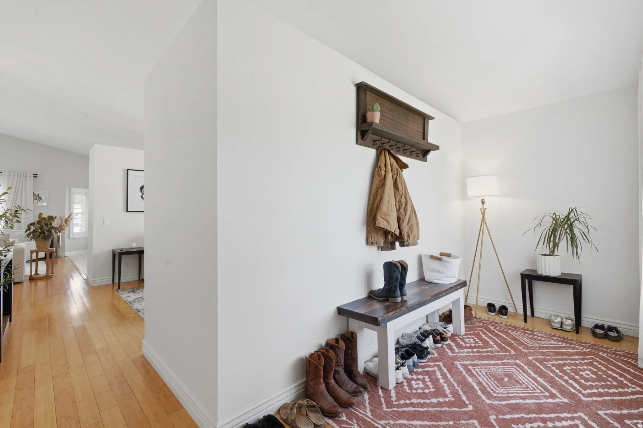 Entryway featuring a wood-finish storage bench with shoe storage, a wall-mounted coat rack, and light-toned walls
