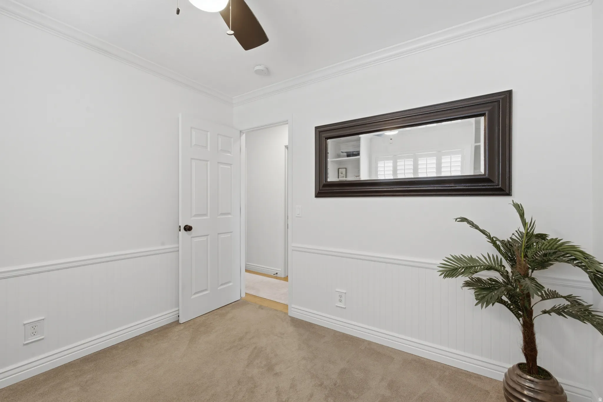 Room featuring crown molding, neutral carpeting, and chair rail with beadboard paneling