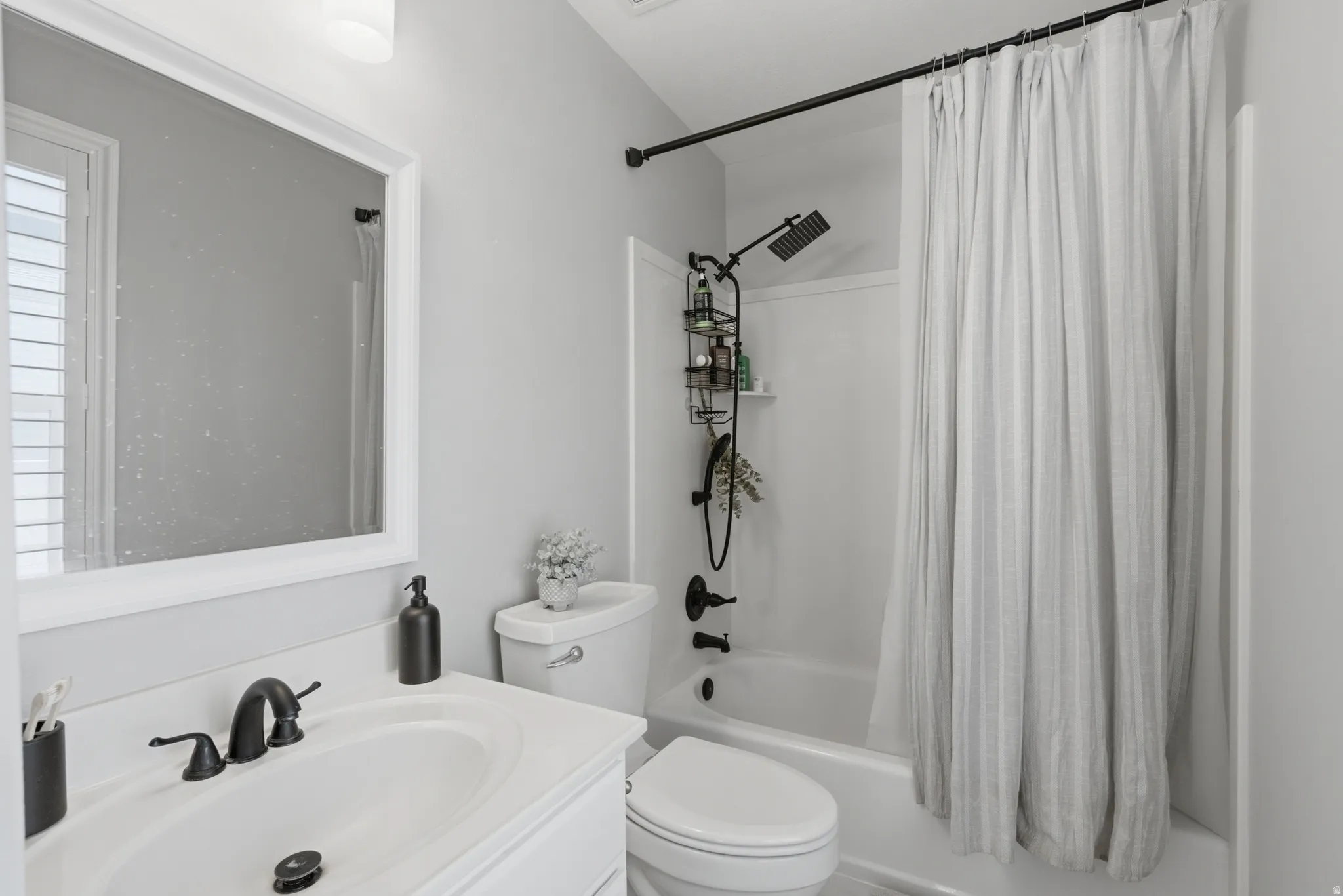 Bathroom featuring a white vanity with an undermount sink, black faucet, and a large framed mirror