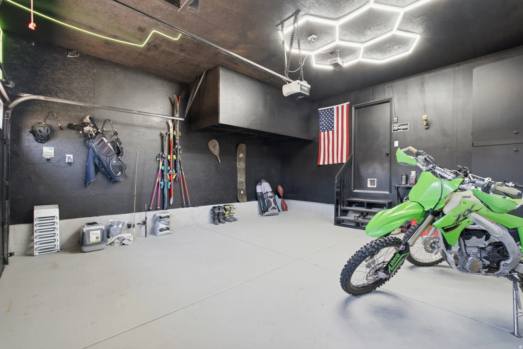 Finished garage featuring a light-colored floor, dark walls, and unique hexagonal ceiling lighting