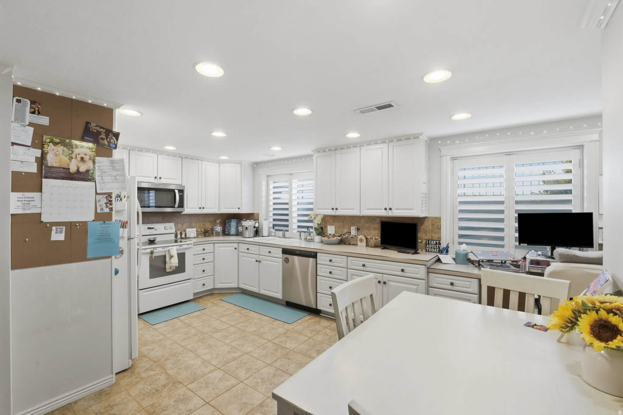Kitchen featuring white cabinetry with dark hardware, recessed lighting, stainless steel appliances, and tile flooring