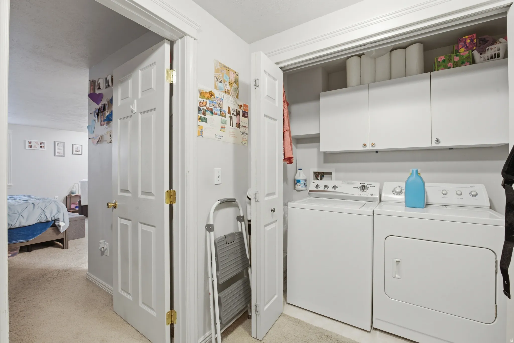 Dedicated laundry area featuring white upper cabinetry, a built-in shelf, and a top-loading washing machine paired with a front-loading dryer