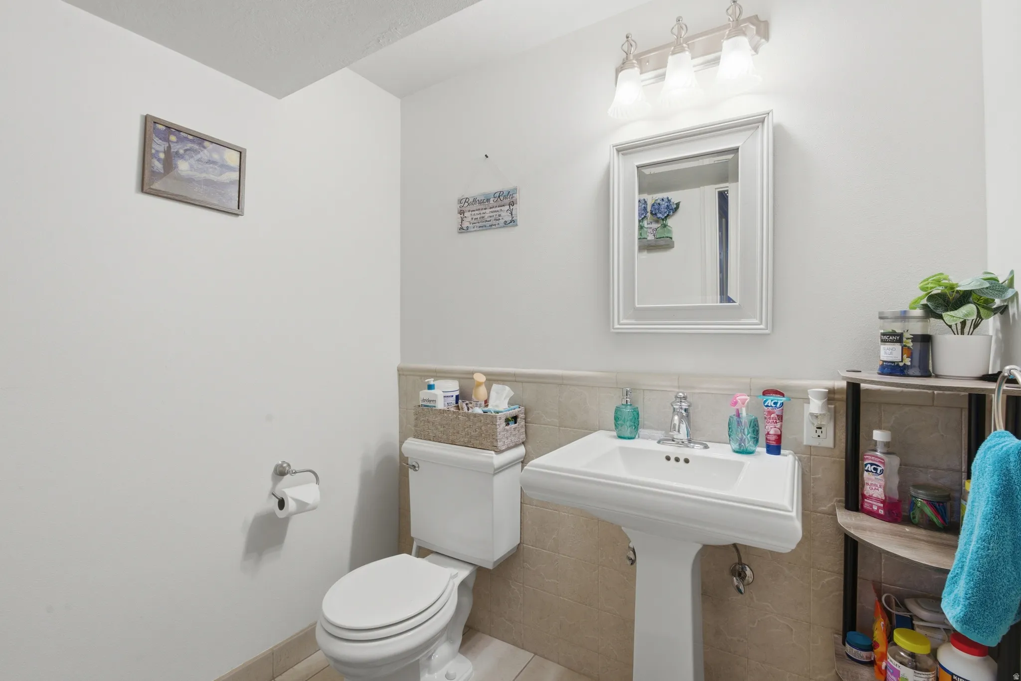 Pedestal sink with chrome faucet, framed mirror, and three-light vanity fixture