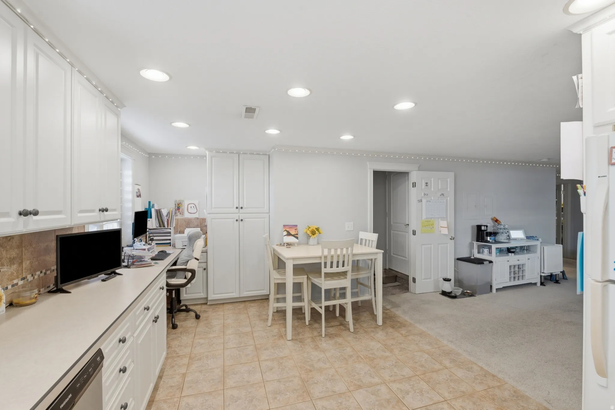 Open-concept kitchen and dining area featuring recessed lighting, extensive white cabinetry, and a tile backsplash