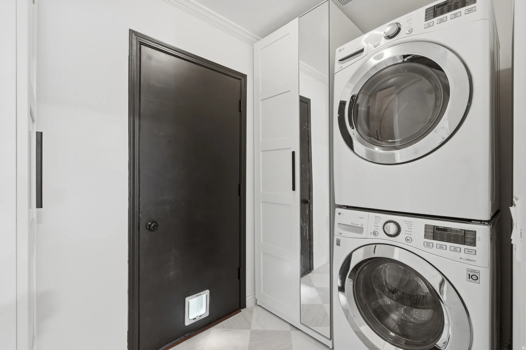 Dedicated laundry area featuring stacked front-loading washer and dryer units