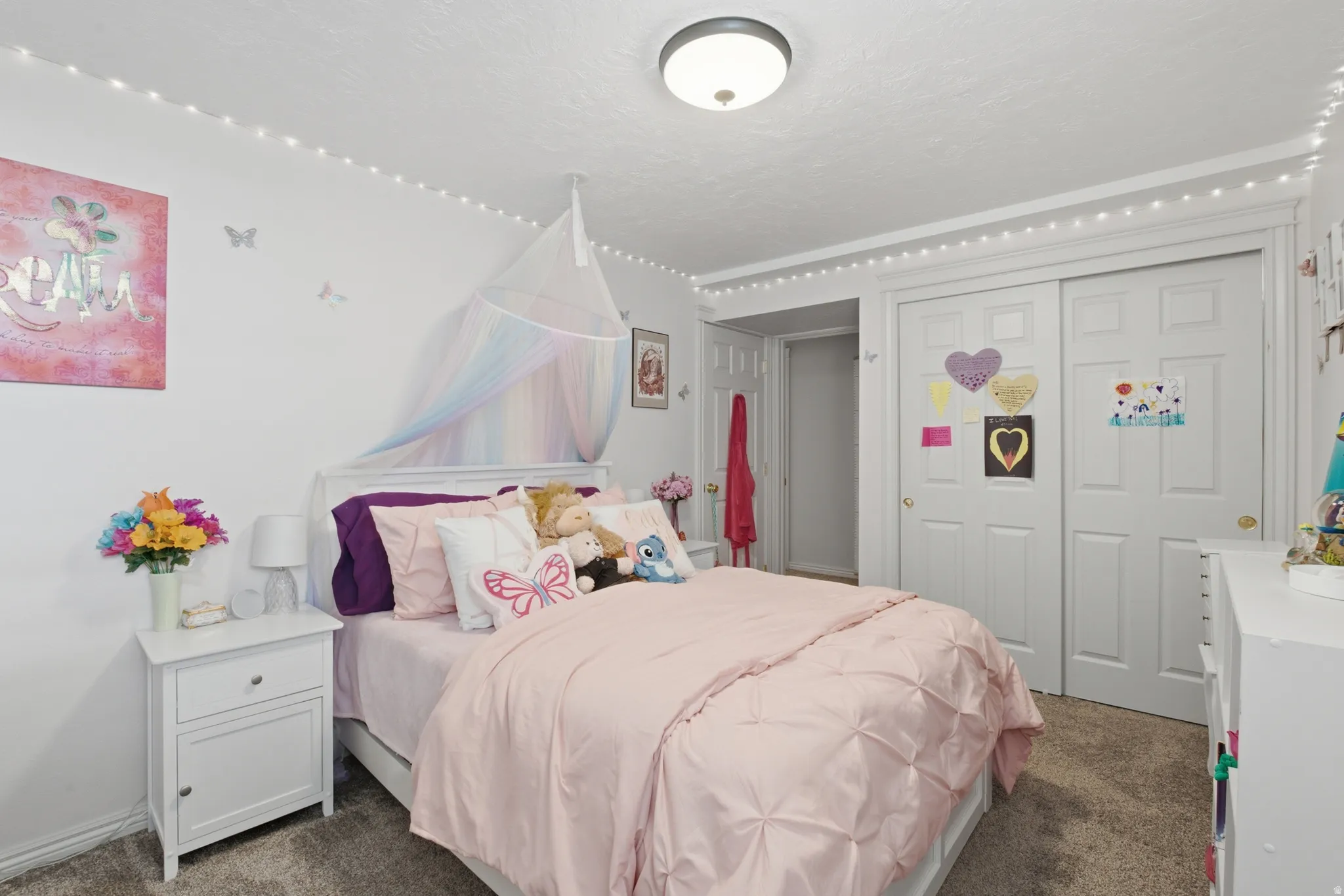 Bedroom featuring neutral carpeting, a built-in closet with bi-fold doors, and a ceiling-mounted light fixture