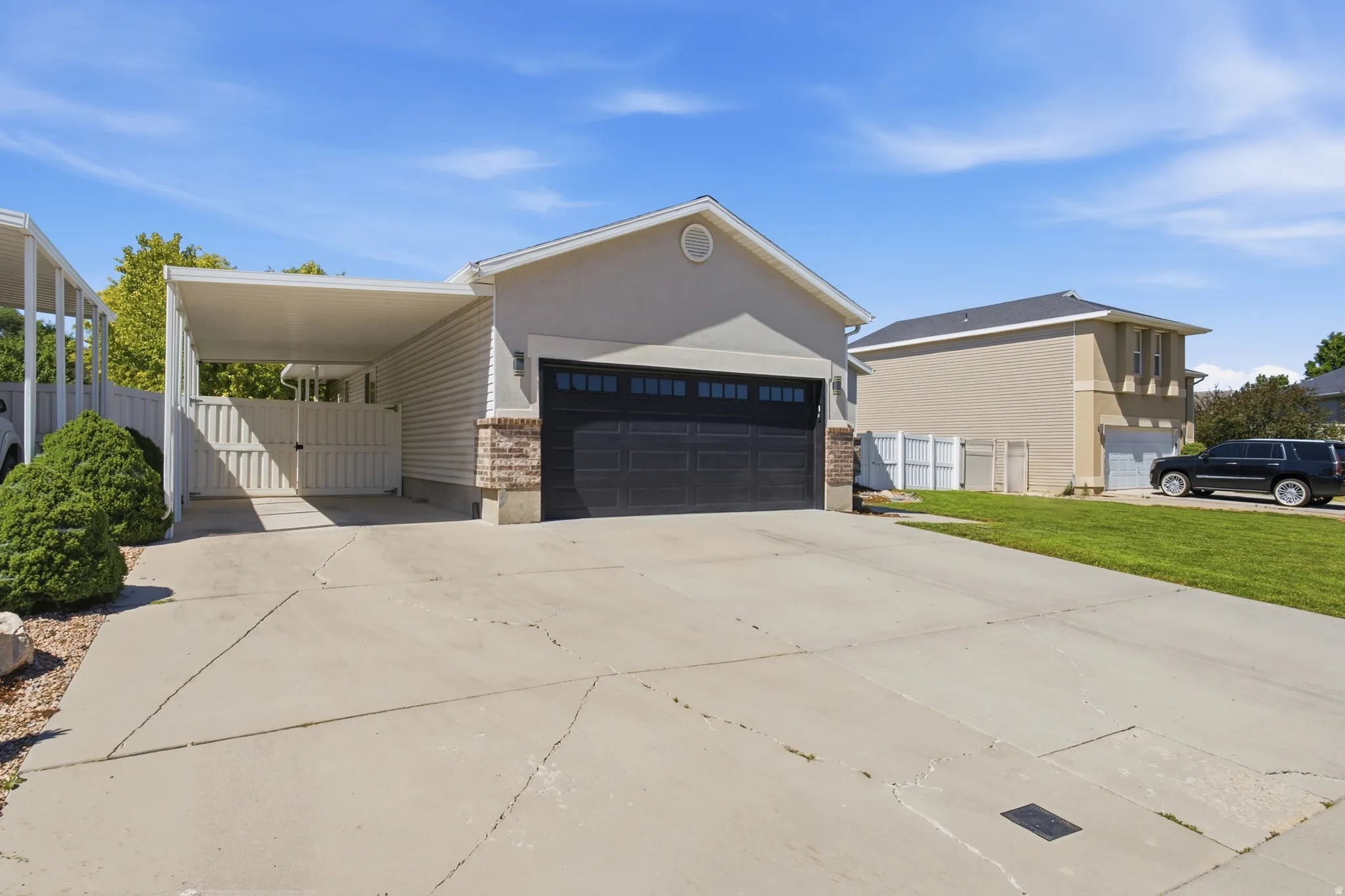Exterior featuring a two-car garage with a dark panel door, a covered side carport, and a concrete driveway