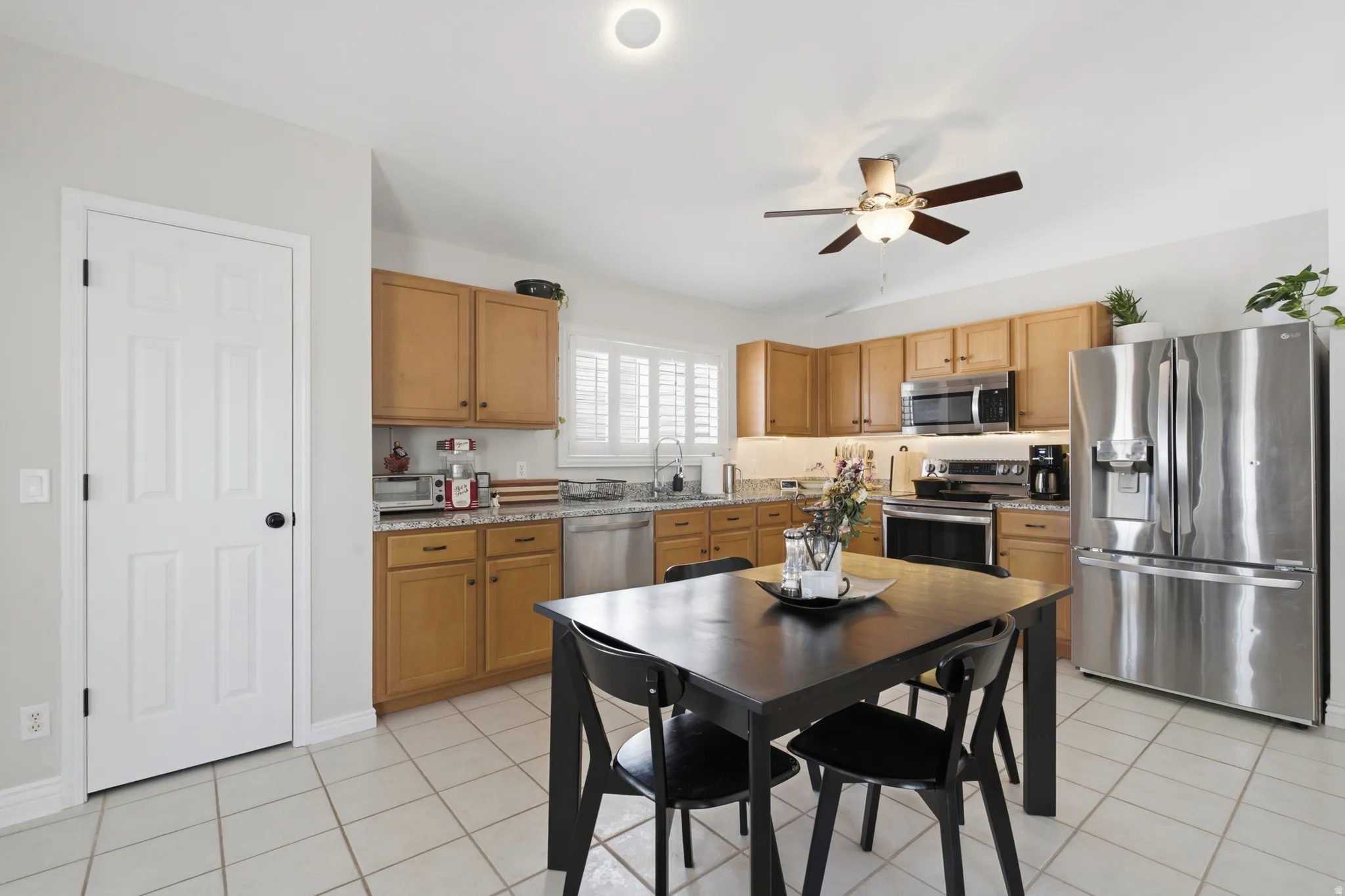 Kitchen featuring wood cabinetry, stainless steel appliances, granite countertops, and white plantation shutters