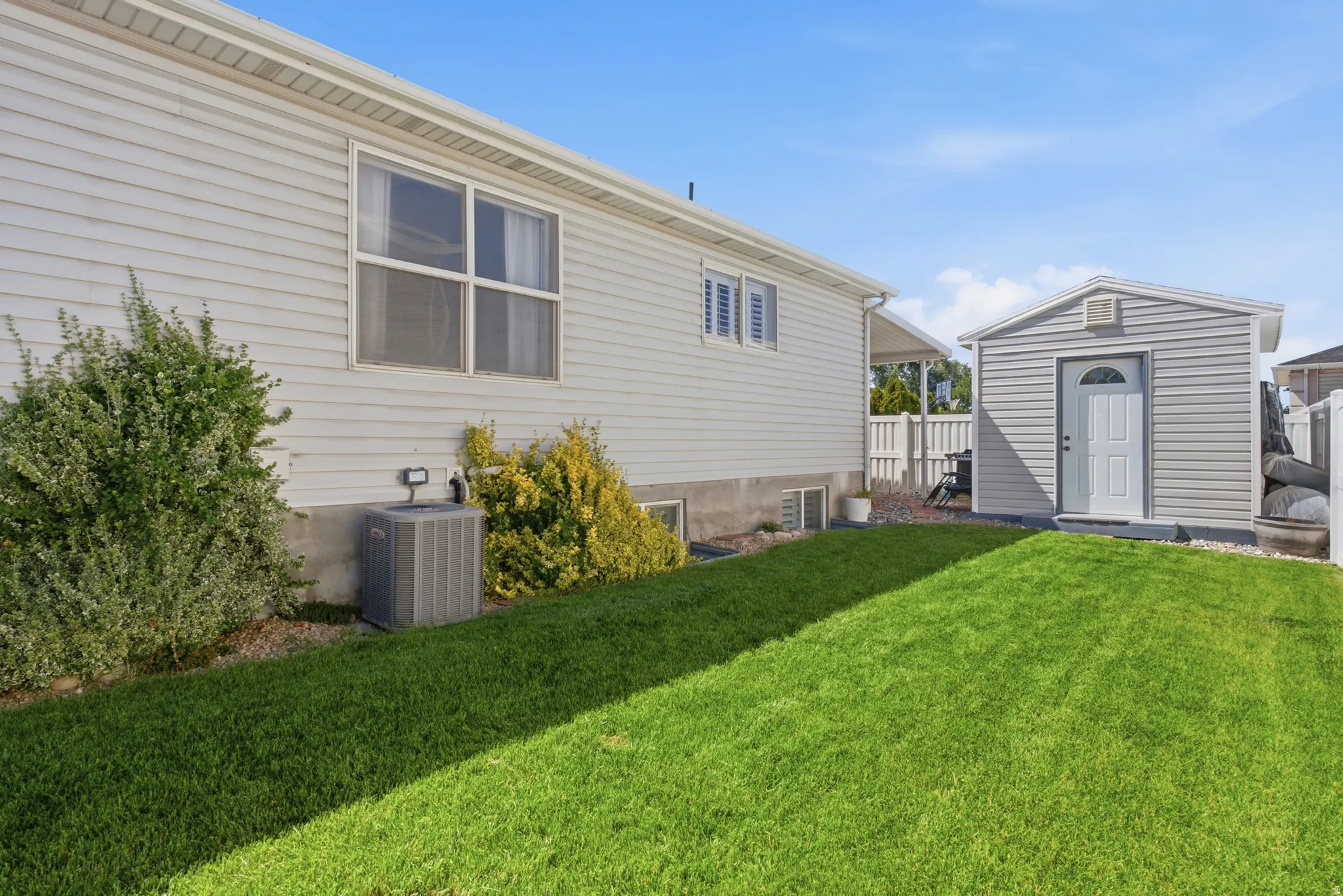 Side lawn with a detached storage shed (owner's use) featuring a white door and siding