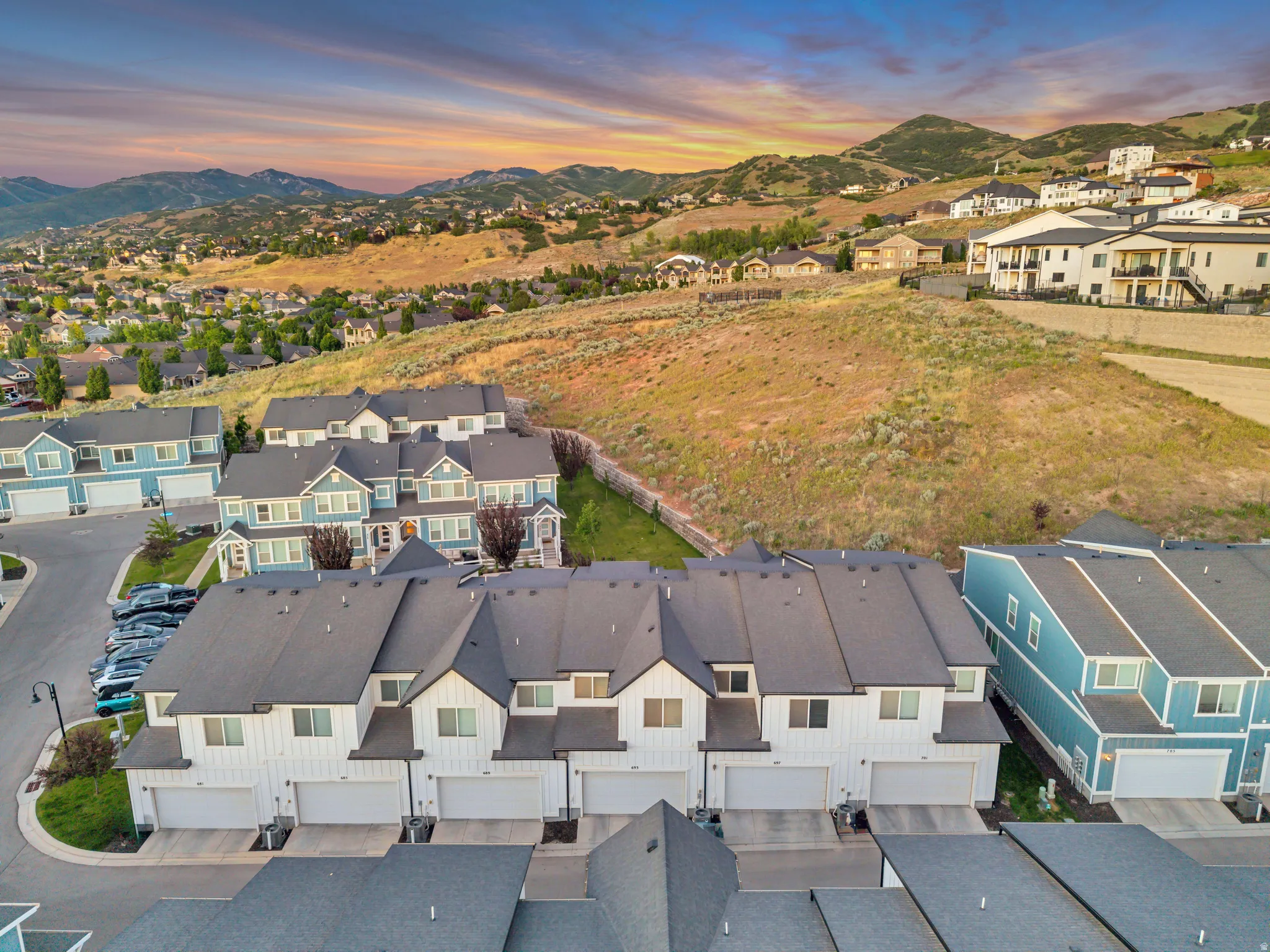 Modern townhome community featuring a consistent architectural style with white and light blue siding, dark gray roofing, and attached garages