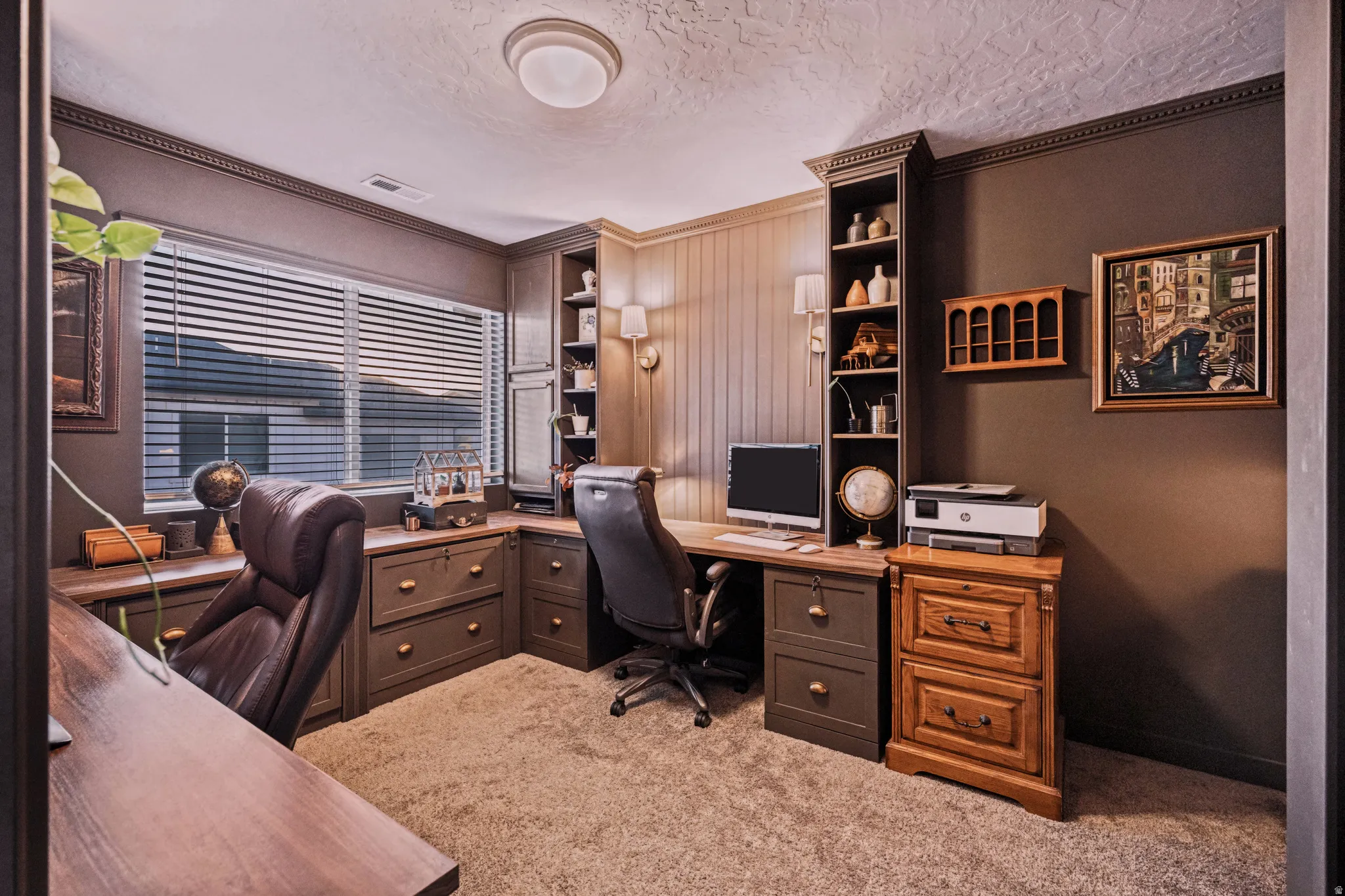 Dedicated office space featuring built-in cabinetry, an integrated desk system, and a window with horizontal blinds