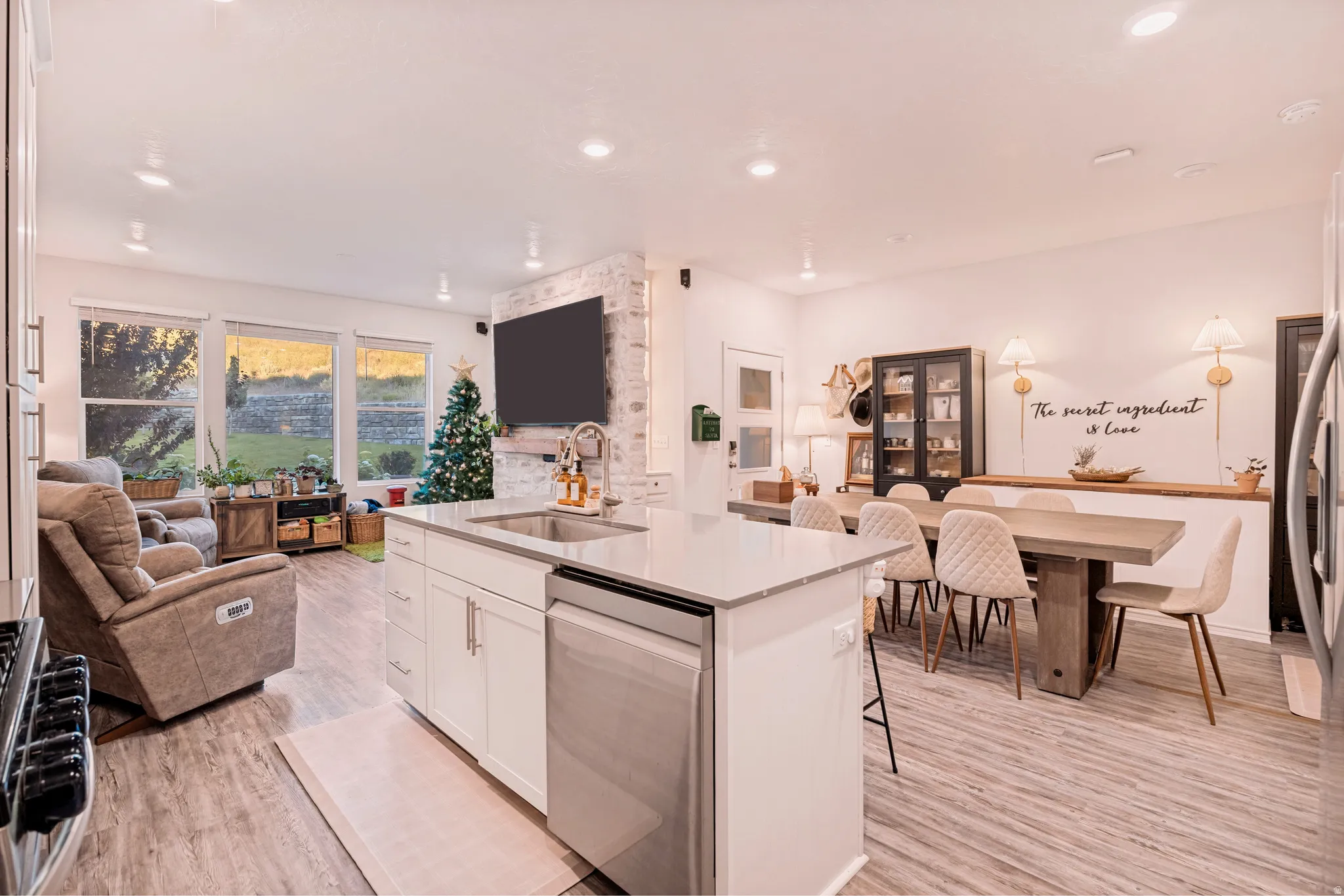 Open-concept living space featuring wood-finish flooring, recessed lighting, and a kitchen island with a stainless steel sink and dishwasher