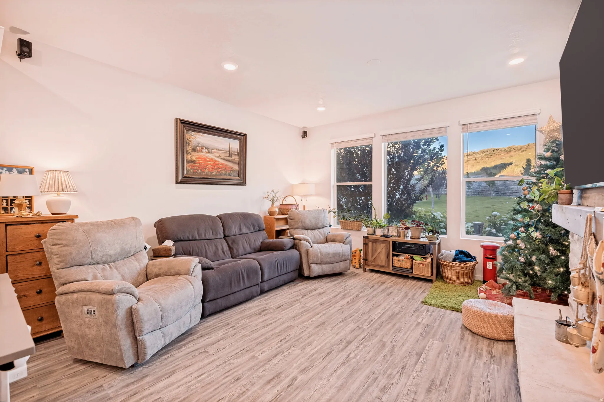 Living area featuring wood-finish flooring, recessed lighting, and a fireplace with a stone mantel
