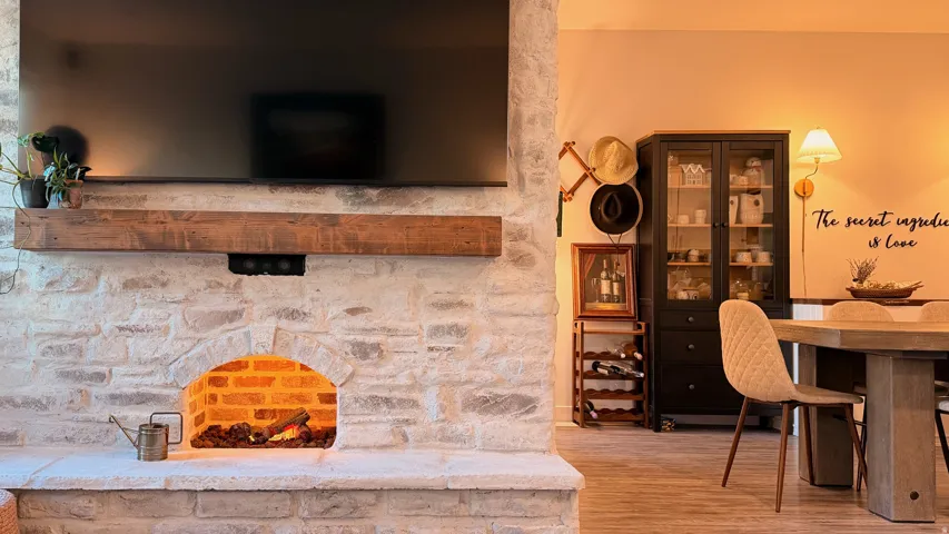 Stone-clad fireplace with a prominent wood mantel, featuring an arched firebox
