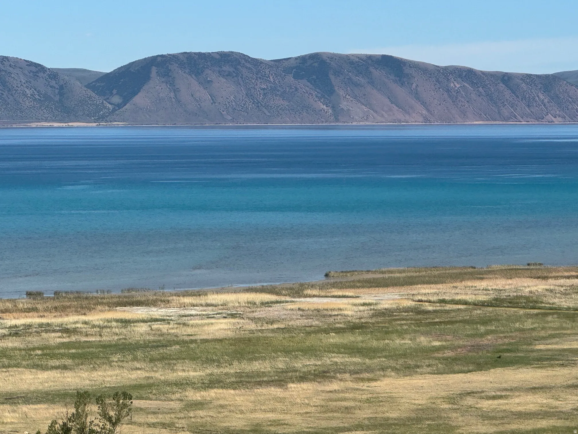 Expansive water body with varying blue hues and distant mountains