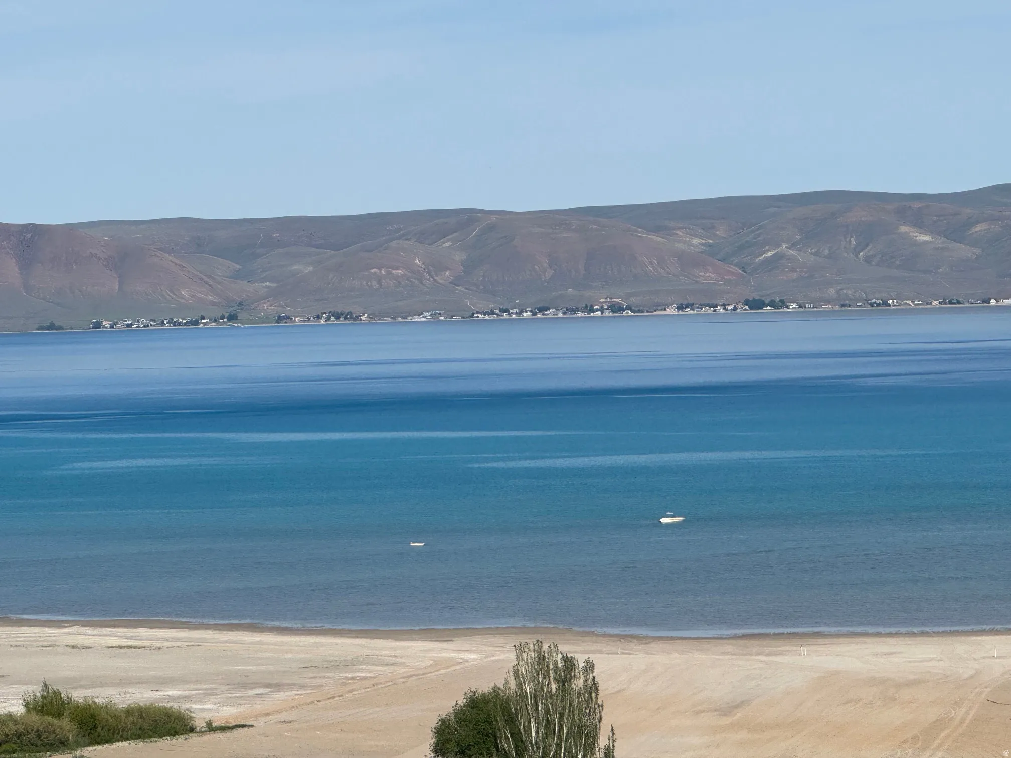 Expansive water body with distant mountains and a sandy shoreline