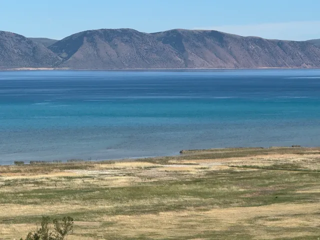 Expansive water body with varying blue hues and distant mountains