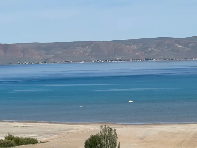 Expansive water body with distant mountains and a sandy shoreline
