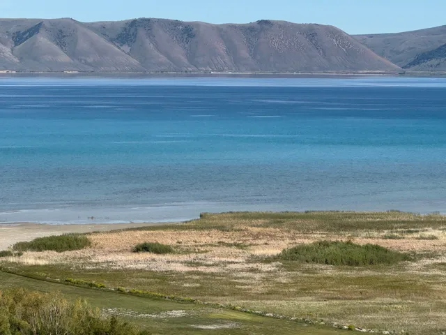 Expansive water body with varying blue hues and distant rolling hills