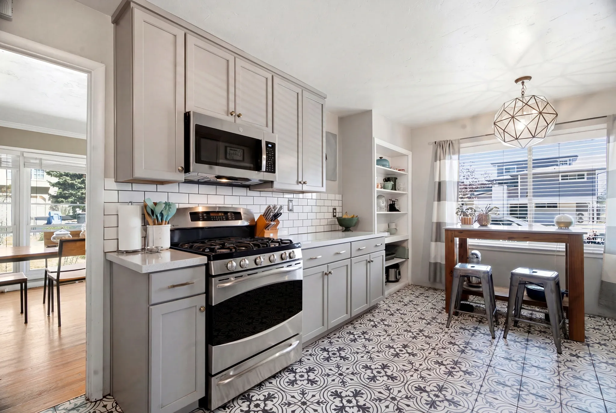 Kitchen featuring patterned floor tile, light gray cabinetry, white subway tile backsplash, stainless steel gas range, and a built-in microwave