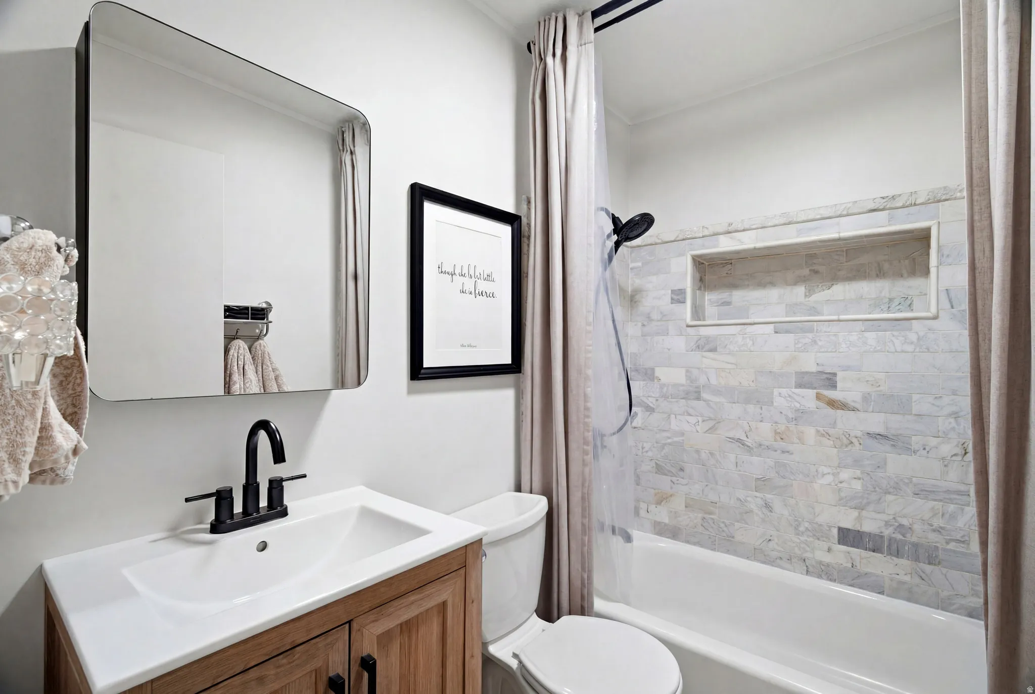 Bathroom featuring a wood-finish vanity with an integrated sink, matte black faucet, and a wall-mounted rectangular mirror
