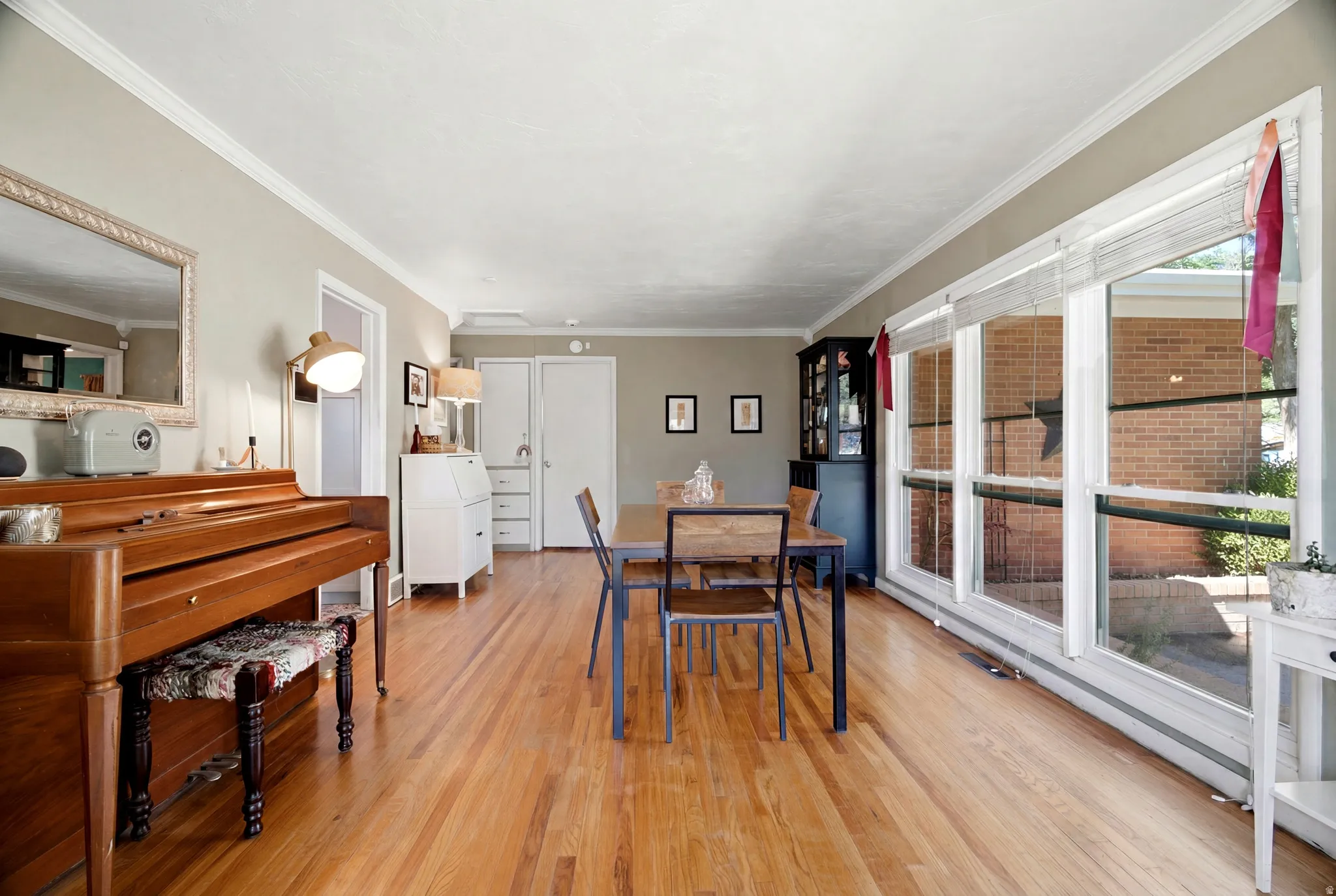 Spacious room featuring wood-finish flooring, a wall of large windows, and crown molding
