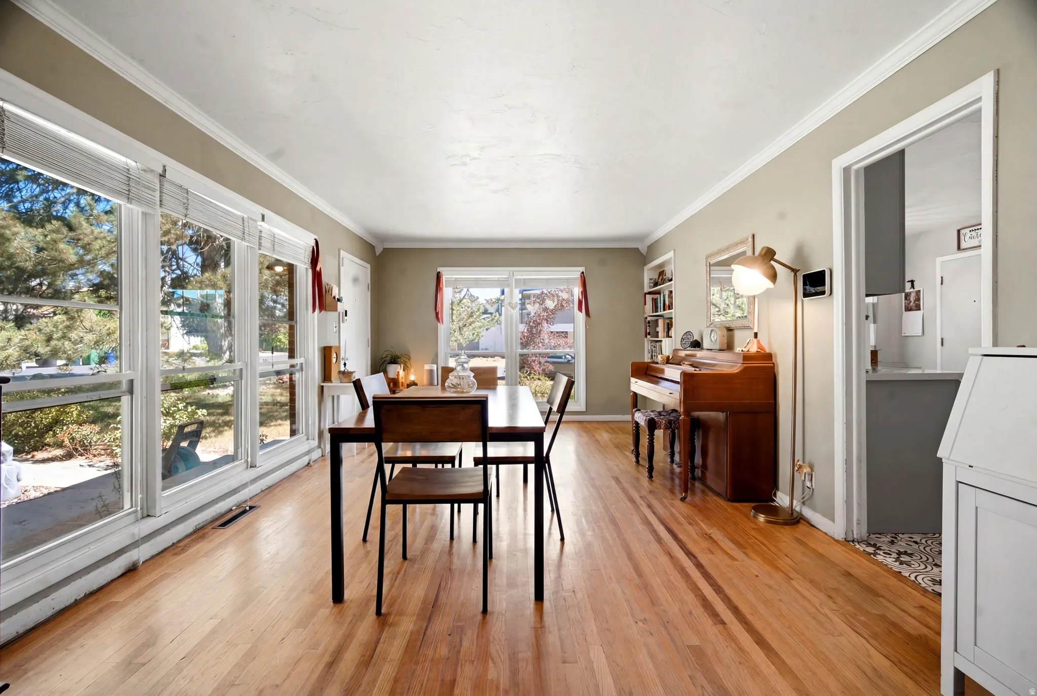 Bright interior space featuring wood-finish flooring, extensive window banks, crown molding, and built-in shelving