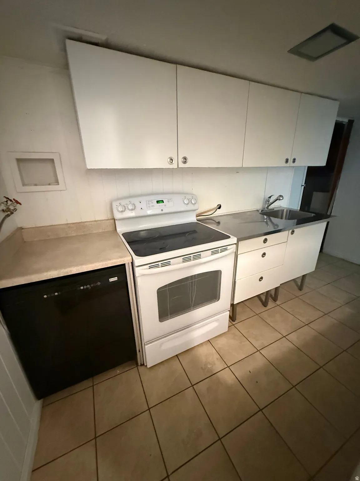 Kitchen area with white cabinetry, a white electric range, a stainless steel sink, black dishwasher, and tile flooring
