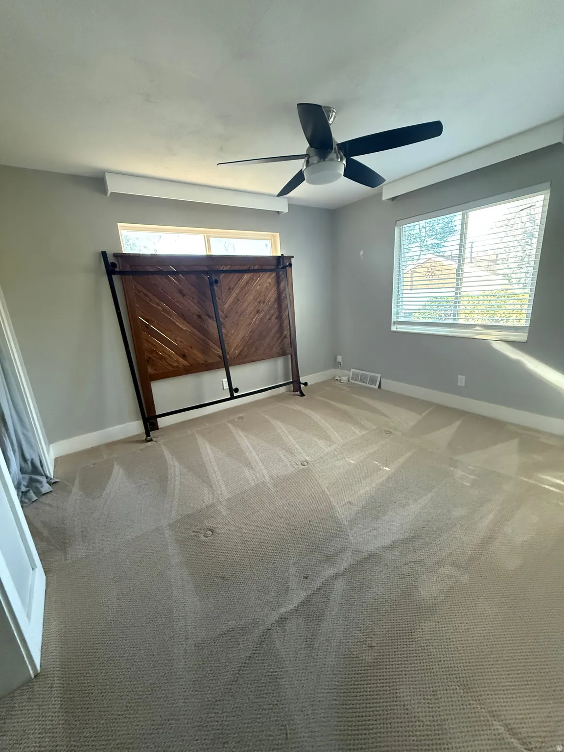 Recessed lighting valances, ceiling fan with integrated lighting, two windows with blinds, and carpet flooring