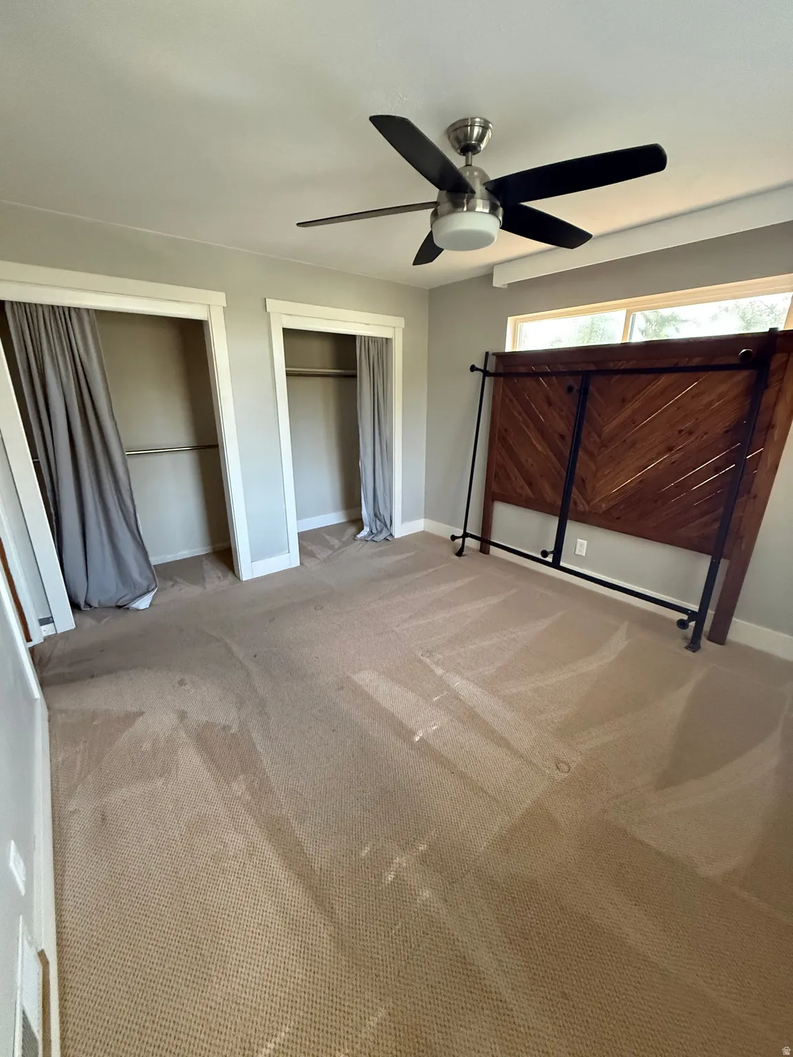Ceiling fan with integrated lighting, two built-in closet spaces, and carpeted flooring